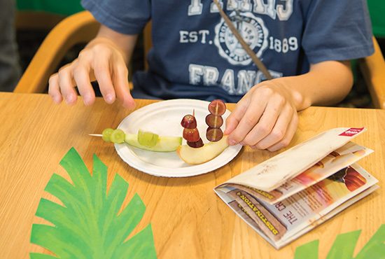 Roadside Diner Station Photo: A child uses apples, toothpicks, and grapes to fashion an edible ship.