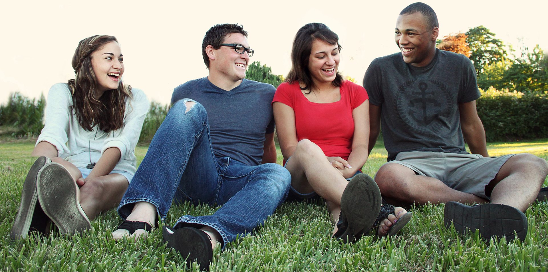 Four Teenagers Sitting in a Field Smiling