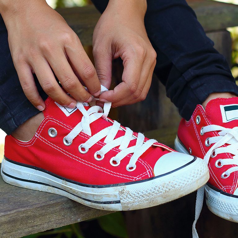 photo of person tying red shoes