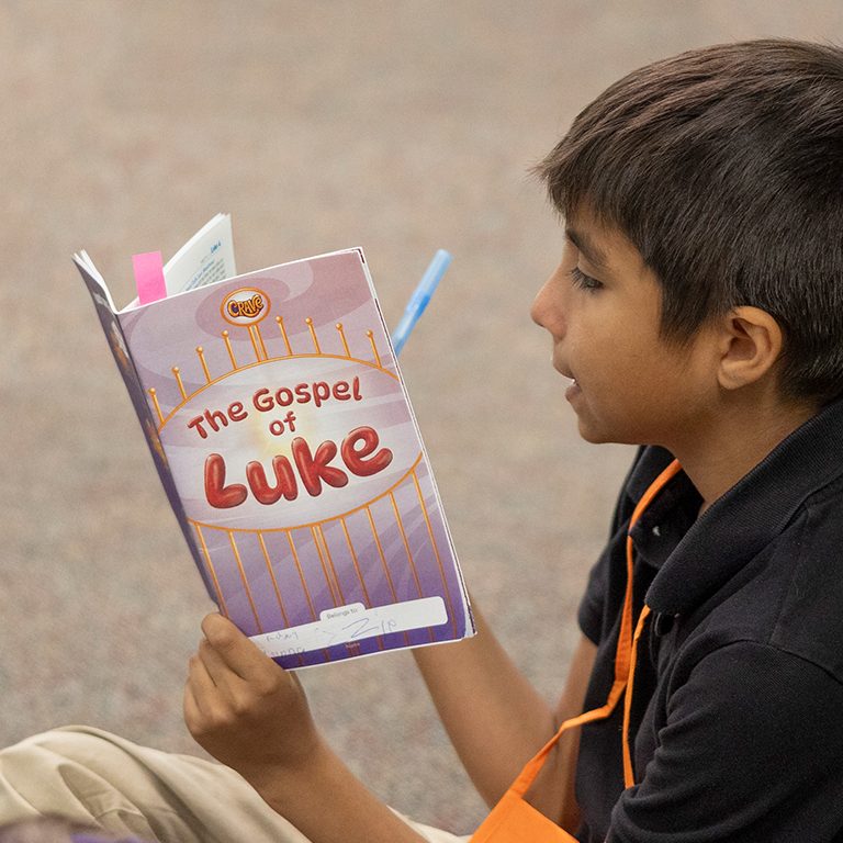 Boy reading The Gospel of Luke Student Book at VBS